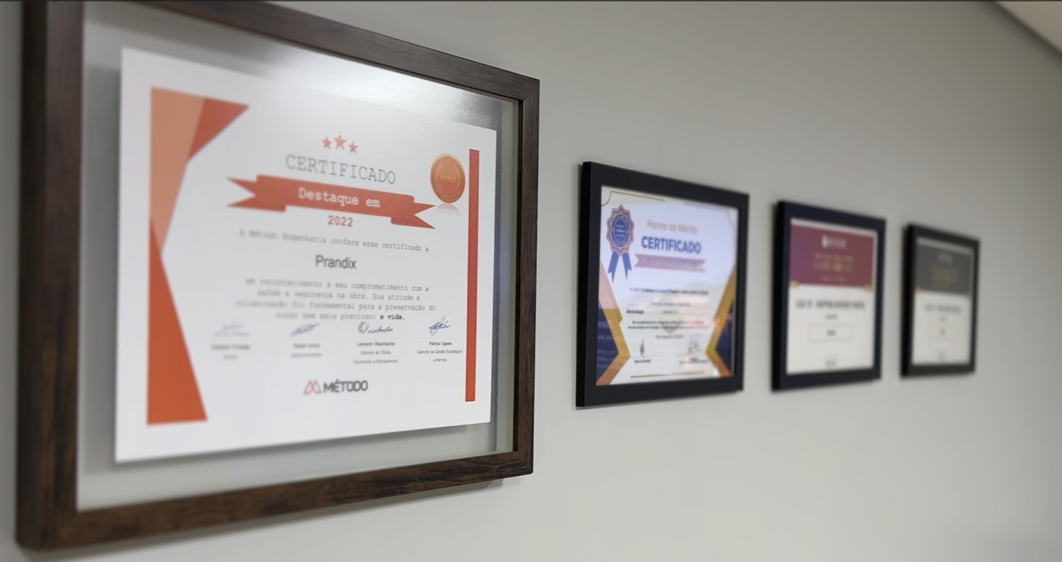 Paredes da Prandix com certificados emoldurados de destaque e premiações de segurança do trabalho e desempenho em obras comerciais.
